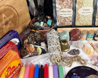 May include: A collection of spiritual and metaphysical items, including candles, crystals, herbs, and a wooden box. The image features colorful candles, small jars, and a bundle of sage. The text "DRAGONS BLOOD" is visible on a box.