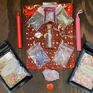 May include: A red and pink love spell kit with a red candle, pink candle, rose quartz crystal, love salt, herbs, and a small glass bottle. The kit is packaged in a red mesh bag with stars and moons.