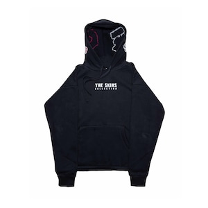 Könnte beinhalten: Schwarzer Kapuzenpullover mit Fronttasche und Kordelzug. Das Kapuzenfutter hat ein rosa-weißes Design. Der Text "THE SKINS COLLECTION" ist weiß auf der Brust aufgedruckt. Ein lässiges, bequemes Kleidungsstück.