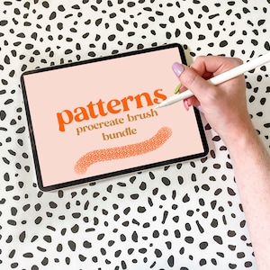 May include: A digital tablet displaying the text "patterns procreate brush bundle" in orange and gold text on a pink background. A hand is holding a white stylus and drawing a pattern on the screen.