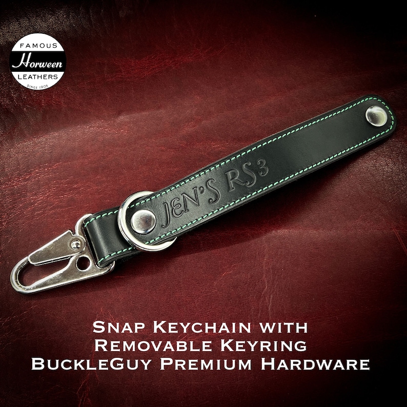 A black Horween leather keychain with a silver snap hook and a green stitched border. The keychain has the text 'JEN'S RS3' embossed on it. The keychain is a snap keychain with a removable keyring and is made with Buckleguy premium hardware.