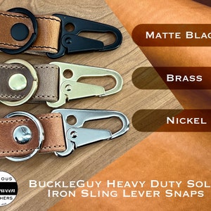 Three leather keychains with premium iron sling lever snaps. The snaps are in three different finishes: matte black, brass, and nickel. The keychains are labeled with the words 'Buckleguy Heavy Duty Solid Iron Sling Lever Snaps' and 'Famous Horween Leathers Since 1905'.