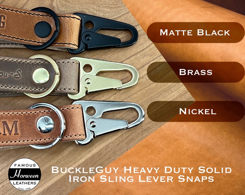 Three leather keychains with premium iron sling lever snaps. The snaps are in three different finishes: matte black, brass, and nickel. The keychains are labeled with the words 'Buckleguy Heavy Duty Solid Iron Sling Lever Snaps' and 'Famous Horween Leathers Since 1905'.