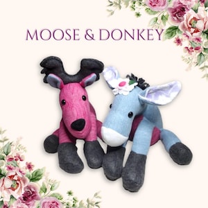 May include: A pink moose and a blue donkey plush toy. Both toys are sitting on a white background. The moose has a black nose and black hooves. The donkey has a white face and black hooves. The donkey has a flower on its head.