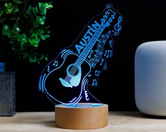 May include: A blue and white personalized guitar-shaped night light with the name "Austin" on it. The light is on a wooden base and has musical notes around it.