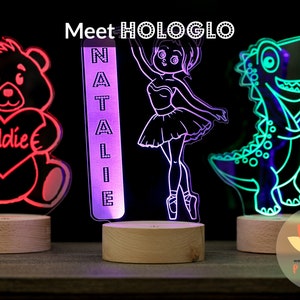 May include: Three personalized LED night lights with different designs. The first is a teddy bear holding a heart with the name "Eddie" on it. The second is a ballerina with the name "Natalie" on it. The third is a dinosaur with the name "Nicholas" on it.