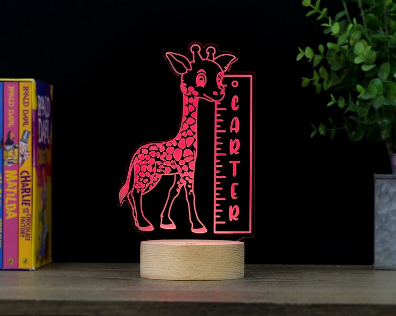 May include: A pink giraffe night light with a wooden base and a height chart that says "CARTER".