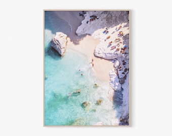 May include: An aerial view of a white sand beach with turquoise water. People are swimming and sunbathing on the beach. The beach is surrounded by white cliffs.