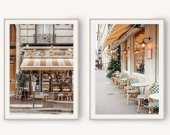 May include: Two framed prints of Parisian cafes. The first print shows a cafe with a striped awning and the text "Le Bossue" above the entrance. The second print shows a cafe with tables and chairs set up outside on the sidewalk.