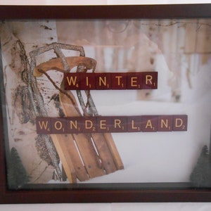 Może przedstawiać: Ramka z obrazem drewnianych sań opartych o brzozę, z wyrazami "WINTER WONDERLAND" ułożonymi z liter z gry Scrabble.