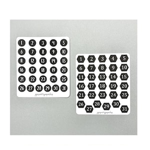 May include: Two sheets of black and white number stickers. One sheet has round stickers with numbers 1-31. The other sheet has hexagonal stickers with numbers 1-31. Both sheets have the text "jojosprettypapershop" at the bottom.