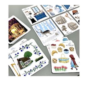 May include: A set of colourful illustrated stickers featuring various themes, including a winter scene with a deer, a gingerbread house, a cottage with blue flowers, and a red hooded girl with a basket. The stickers are printed on white paper and have a "Jojo's Pretty Paper Shop" logo.
