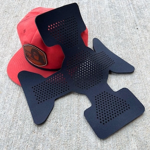 May include: A black, padded, and perforated hat liner with a red hat underneath. The liner has a unique shape with a large, central section and two smaller sections on either side.
