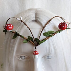 May include: A woodland-themed crown with brown branches, green leaves, and red and white mushroom accents.