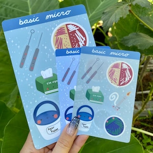 May include: Three sticker sheets with a blue background and white stars. The stickers feature illustrations of lab equipment, including petri dishes, agar flakes, kim wipes, and inoculation loops. The text "basic micro" appears on each sheet.