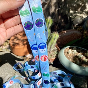 May include: Two blue and white patterned lanyards with a variety of cute illustrations, including a plant, a bucket, a needle, and a tissue box. The lanyards are made of a soft, durable material and are perfect for holding keys, badges, or other small items.