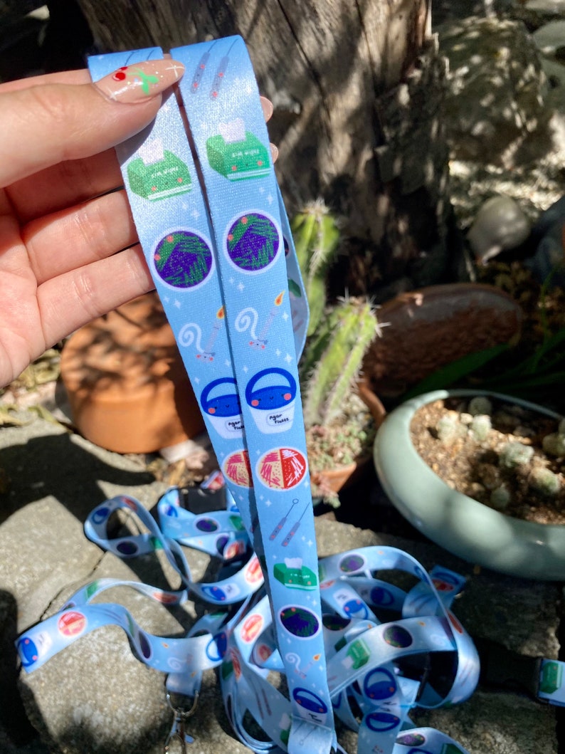 May include: Two blue and white patterned lanyards with a variety of cute illustrations, including a plant, a bucket, a needle, and a tissue box. The lanyards are made of a soft, durable material and are perfect for holding keys, badges, or other small items.
