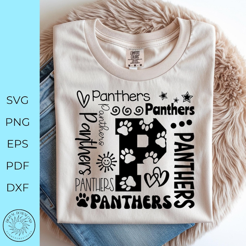May include: Cream-colored t-shirt with the word "Panthers" in various fonts and designs. A large letter "P" is filled with paw prints. The shirt is folded on top of blue jeans and a fluffy, light brown surface.