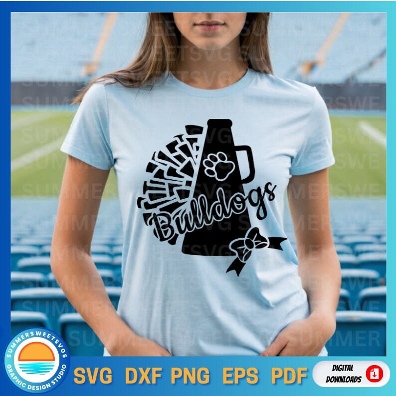 May include: Light blue t-shirt featuring a black graphic of a megaphone, pom-poms, and the word "Bulldogs." A paw print and bow are also included in the design. The shirt is a digital download.