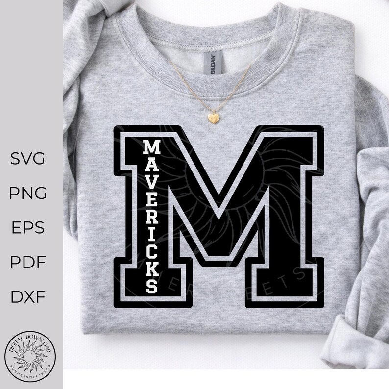 May include: A light gray crewneck sweatshirt featuring a large black block letter M with a white outline. The word MAVERICKS is printed vertically in white capital letters inside the left side of the M. A gold heart pendant necklace rests on the collar.