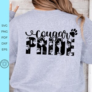 Peut inclure: Un sweat-shirt gris clair avec l'inscription "Cougar Pride" en &eacute;criture noire et en lettres majuscules. Le mot "Pride" est rempli d'empreintes de pattes. Le sweat-shirt a un col rond et des manches longues.