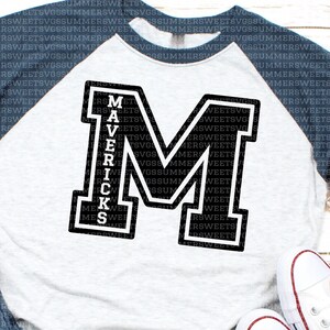 May include: A baseball-style raglan shirt with a light gray heathered torso and dark navy blue sleeves. The front features a large black block letter M with a white outline, and the word MAVERICKS is printed vertically in white inside the letter.
