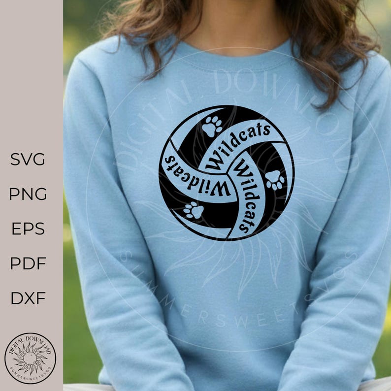 May include: Pale blue sweatshirt with a black and white Wildcats design. The design is a stylized volleyball with paw prints and the word "Wildcats" in a curved font. The image also includes the text "SVG, PNG, EPS, PDF, DXF".