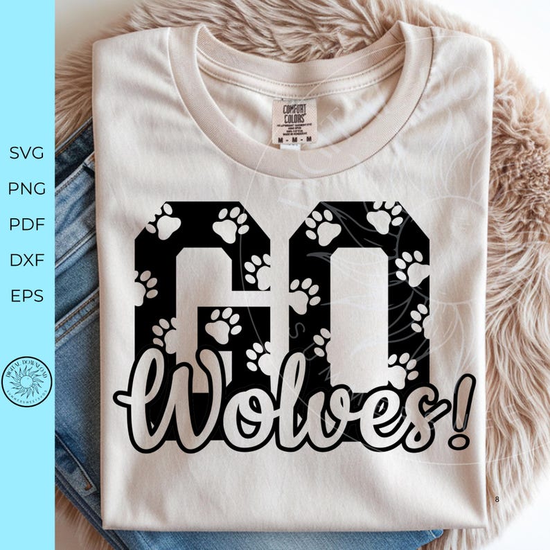 May include: A cream-colored short-sleeve t-shirt featuring a large black graphic with the text GO WOLVES! The letters GO are filled with a white paw print pattern, while the word WOLVES! is written in a white script font below the block letters.