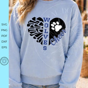 May include: A light blue long-sleeve sweatshirt featuring a black heart graphic divided by the vertical blue text WOLVES. The left side of the heart shows a black pom-pom design, while the right side features a white paw print and blue script text Cheer.