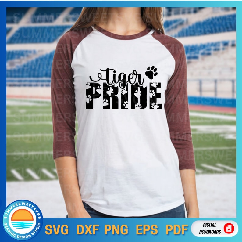 May include: A white raglan t-shirt with maroon three-quarter length sleeves. The front features the black text "tiger PRIDE" with a paw print icon. The word "PRIDE" is filled with a repeating pattern of small white paw prints.