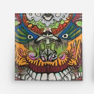May include: A square button with a colorful, abstract design featuring a variety of shapes, lines, and colors, including green, orange, blue, and red. The design is reminiscent of a face with eyes, a nose, and a mouth.
