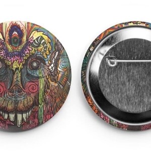 Puede incluir: Un botón redondo con un diseño psicodélico colorido que presenta una cara con un tercer ojo. El botón tiene una parte posterior plateada con un alfiler.