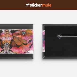 Puede incluir: Un botón negro y blanco con un diseño abstracto de mariposa colorida en la parte delantera y un alfiler en la parte posterior.