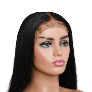 May include: A black, long, straight hair wig on a mannequin head. The wig features a natural-looking hairline and is styled with a center part. The mannequin has a fair complexion, with makeup including dark eyeshadow and pink lipstick.