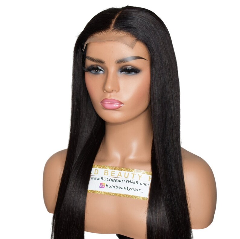 May include: A long, straight black wig with a lace front is displayed on a mannequin head. The wig has a natural part and a sleek, shiny appearance. The mannequin has makeup and a neutral expression. The text on the mannequin reads "BOLD BEAUTY HAIR".