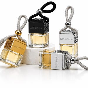 May include: Several car air fresheners with square glass bottles filled with a yellow liquid. The tops are silver, gold, and black with the text "Car Perfume". Each has a decorative cord for hanging.