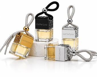 May include: A collection of car air fresheners. Each has a square glass bottle containing a yellow liquid. The tops are silver, gold, and black, with the text "Car Perfume". They have decorative cords for hanging.
