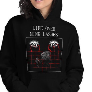 Puede incluir: Sudadera con capucha negra con un estampado gráfico de dos ojos con lágrimas rojas y el texto "LIFE OVER MINK LASHES" en blanco.