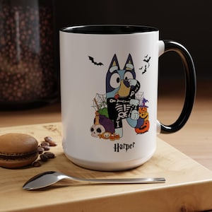 Puede incluir: Taza de cerámica blanca con asa e interior negros. La taza presenta un perro de dibujos animados con disfraz de esqueleto, murciélagos, una telaraña y calabazas. El nombre "Harper" está escrito en la taza con una fuente gótica.
