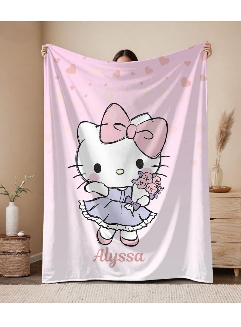 May include: Pink blanket featuring a cartoon cat character with a large pink bow, holding flowers, and wearing a lavender dress. The blanket has a pink heart pattern and the name "Alyssa" is written on it.