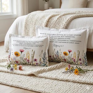 Puede incluir: Dos fundas de almohada blancas con diseños florales y texto de Filipenses 4:6-7. Las fundas de almohada presentan un borde floral estilo acuarela con flores amarillas, rosas y moradas. El texto dice: "No se preocupen por nada..."