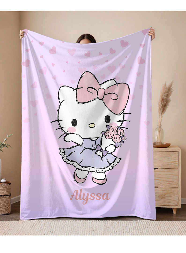 May include: A light purple blanket featuring a cartoon character with a large pink bow, holding flowers. The character is wearing a lavender dress. The blanket has a heart pattern and the name "Alyssa" is printed on it.