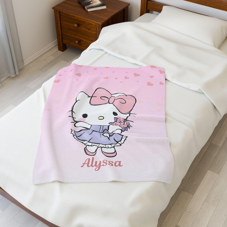 May include: A pink blanket featuring a cartoon character with a large pink bow, holding flowers, and wearing a purple dress. The blanket has a pink heart pattern and the name "Alyssa" printed on it.