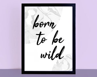 May include: A framed art print with the words "born to be wild" in black script. The background features a white and gray marbled design. The frame is black, and the print is displayed against a light purple background.