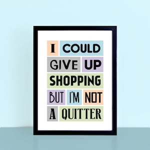 May include: A black framed print with a white background and colourful text that reads "I could give up shopping but I'm not a quitter".