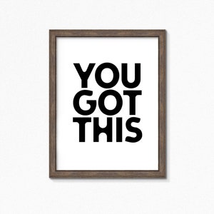 May include: A framed print with the words "YOU GOT THIS" in bold black letters on a white background. The frame is a dark brown color, and the print is centered within the frame.