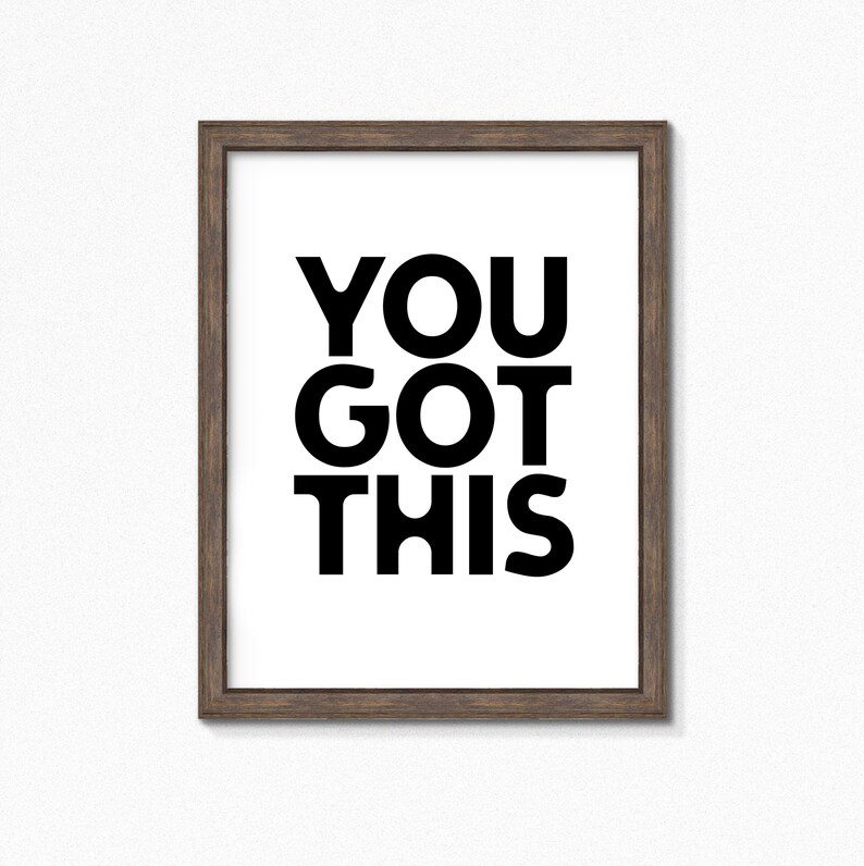 May include: A framed print with the words "YOU GOT THIS" in bold black letters on a white background. The frame is a dark brown color, and the print is centered within the frame.
