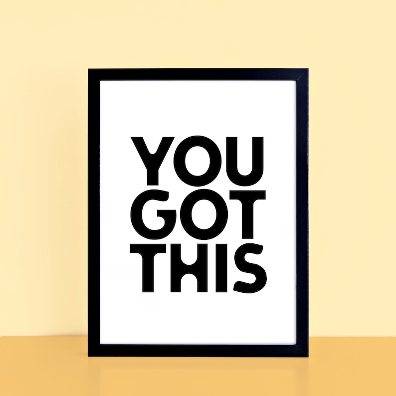 May include: A framed print with the words "YOU GOT THIS" in bold black letters on a white background. The frame is black, and the print is displayed against a light yellow background.