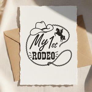 May include: A white card with the text "My 1st Rodeo" in a black, Western-style font, encircled by a rope design. A cowboy hat and a silhouette of a horse and rider are also featured.