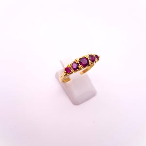 Peut inclure: Une bague en or avec cinq pierres précieuses de couleur rubis rouge serties en rangée.